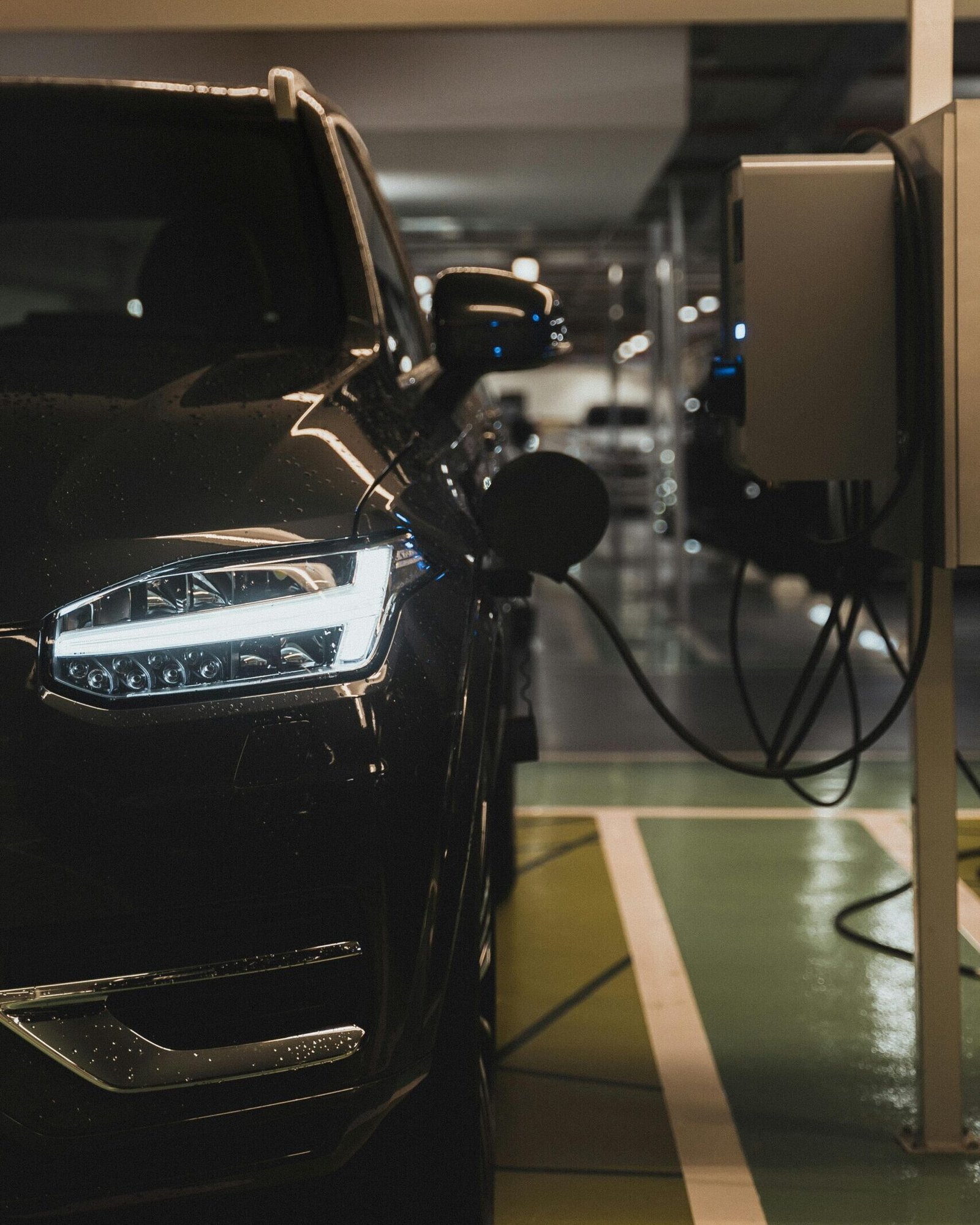 Luxury electric car charging at a station in Curitiba parking garage.