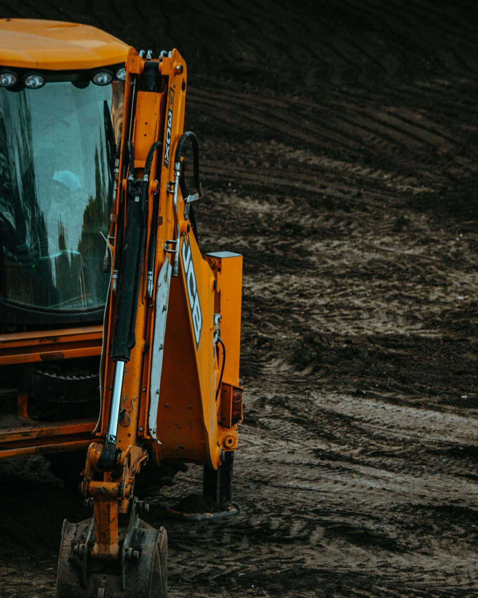 Close-up of a yellow excavator on a construction site with muddy terrain.