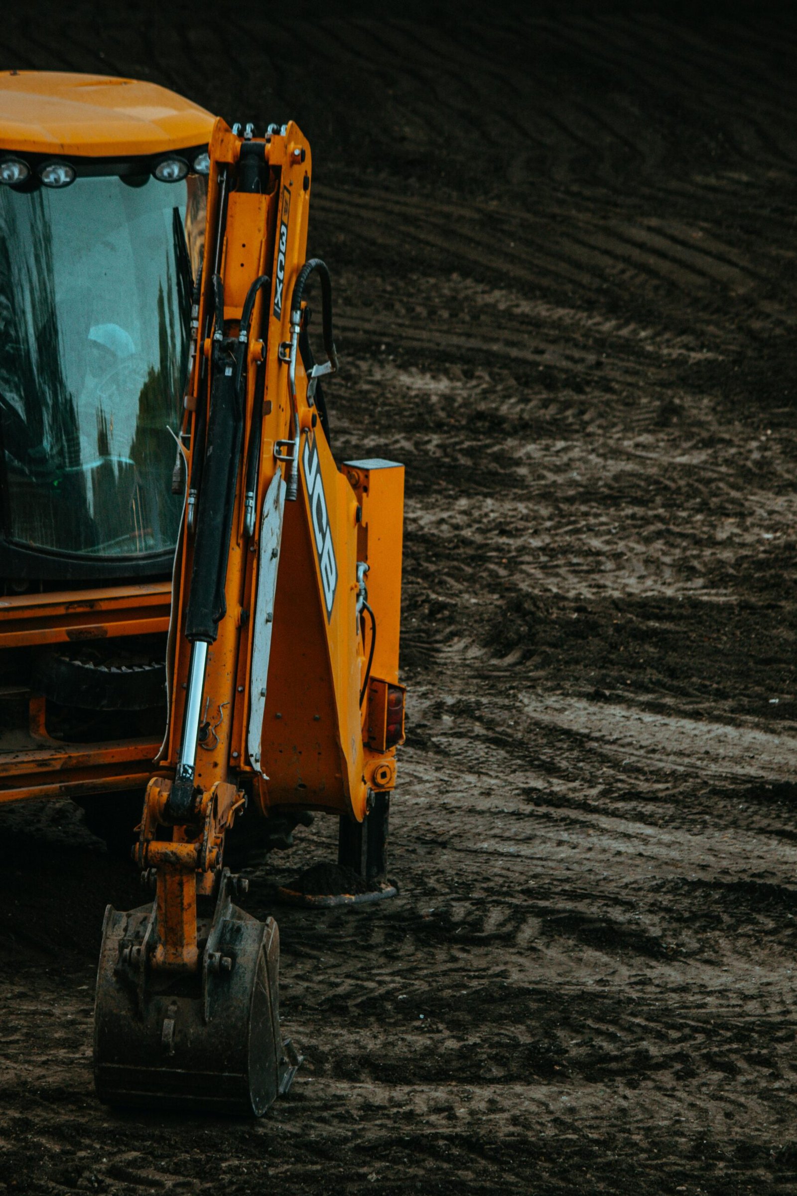 Close-up of a yellow excavator on a construction site with muddy terrain.